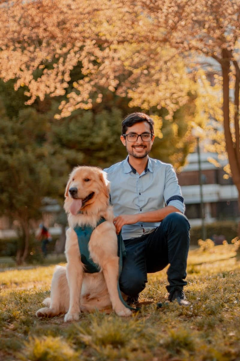 Humane Society of Pinellas man in blue dress shirt sitting beside brown dog during daytime